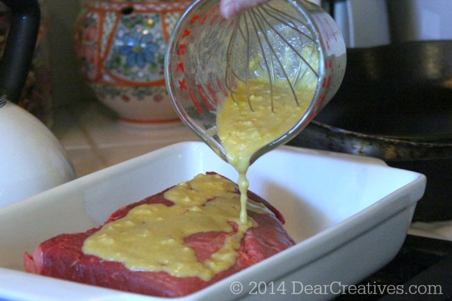 pouring herb mustard on roast 