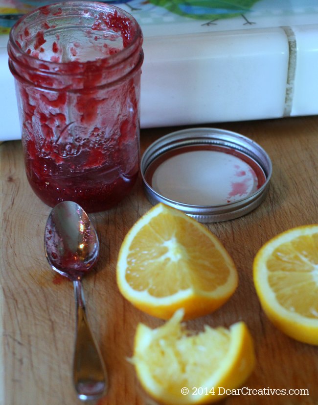 Homemade Cranberry Sauce Raspberry Jam in a jar and orange slices_