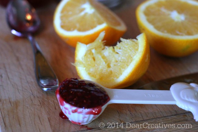 homemade cranberry sauce raspberry sauce measured in a tablespoon and quartered orange_