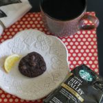 Coffee Lovers Coffee and a bag of Starbucks Coffee next to a plate with a lemon and chocolate cookie