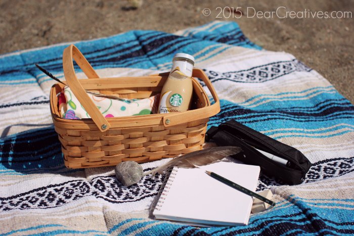 Drawing Supplies and iced coffee on a beach blanket