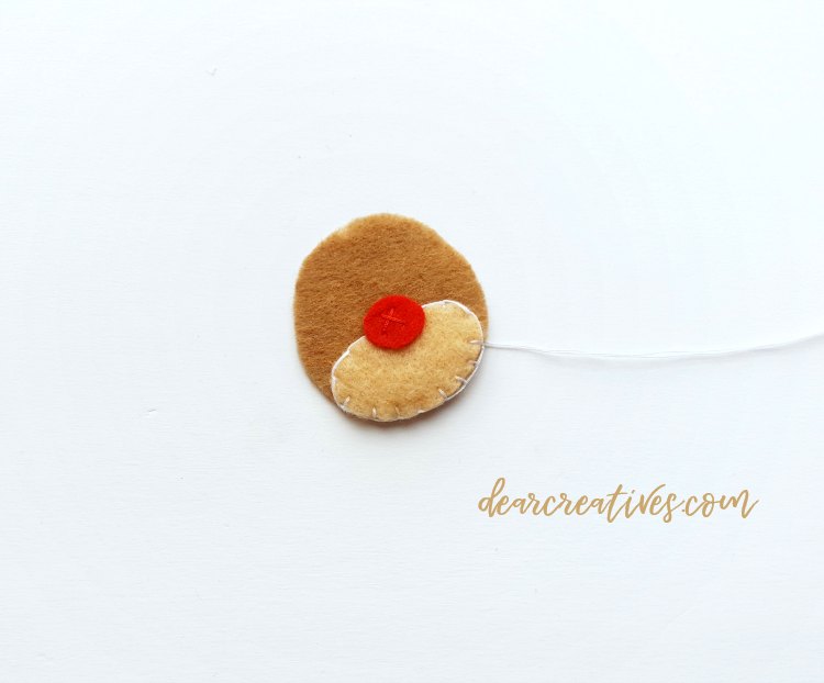 Sewing on the nose for Rudolph the red nosed reindeer. Felt Christmas ornament Step 2 of the diy DearCreatives.com