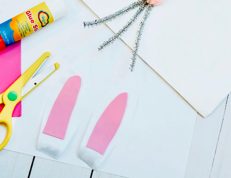 Cutting bunny ears to glue onto the bunny bag. How to make a bunny bag at DearCreatives.com #nosew #bunnybag #bunnypaperbag #dearcreatives