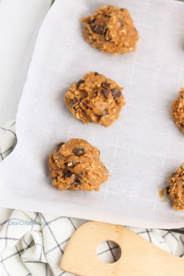 cookie dough on parchment paper on a baking sheet. Pumpkin oatmeal cookies recipe at DearCreatives.com