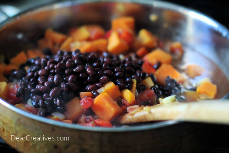 Adding black beans, tomato sauce to the skillet of vegetables for chili. DearCreatives.com