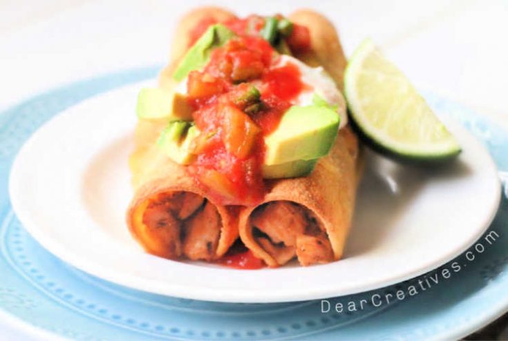 Chicken Taquitos on a plate garnished with sour cream, avocado and salsa with a lime. - DearCreatives.com